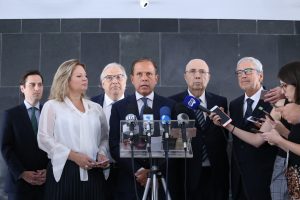 doria falando à imprensa com autoridades ao seu redor