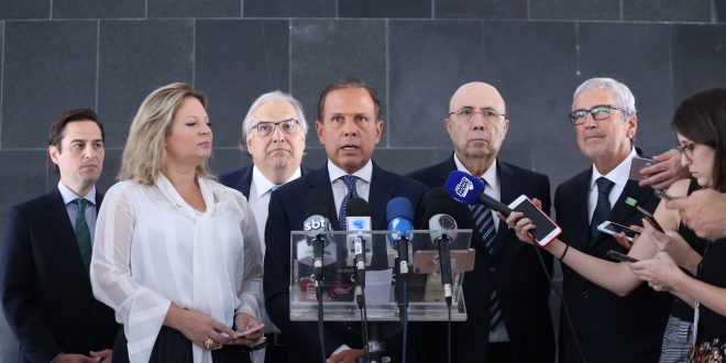 doria falando à imprensa com autoridades ao seu redor