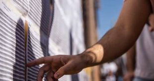 detalhe da mão de um candidato conferindo listas de aprovados