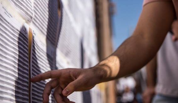 detalhe da mão de um candidato conferindo listas de aprovados