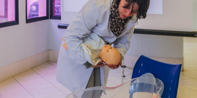 médica manipulando boneca em palestra sobre gravidez de alto risco