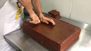 uma grande bananada sendo fatiada em cubos menores