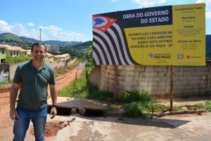 vereador cabo jean posa ao lado de placa informativa da obra de asfaltamento