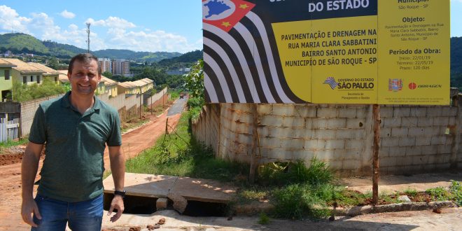 vereador cabo jean posa ao lado de placa informativa da obra de asfaltamento