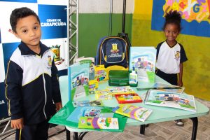 dois alunos posam ao lado de mesa com novos materiais