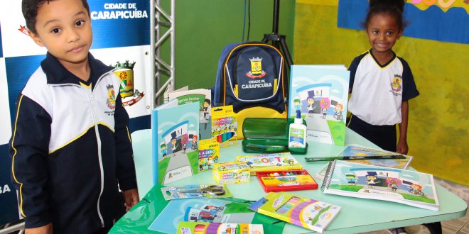 dois alunos posam ao lado de mesa com novos materiais