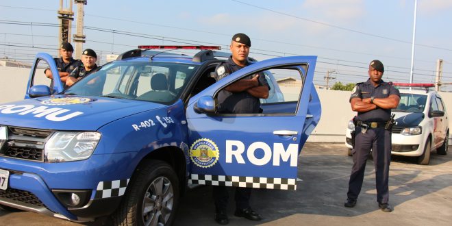uma viatura da romu da guarda civil de carapicuíba com quatro guardas posando em volta com uma viatura da guarda ao fundo