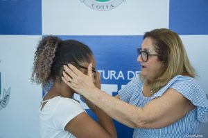 secretária de educação neusa abreu coloca óculos em criança