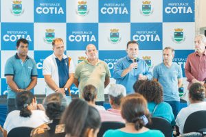 prefeito discursa em palco com autoridades ao lado