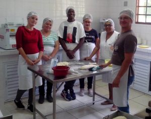 participantes do curso de panificação artesanal posam para foto em volta de mesa