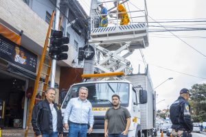 um agente de trânsito, o secretário joaquim brechó e o engenheiro fernando posam para foto diante de caminhão que trabalha na instalação do semáforo