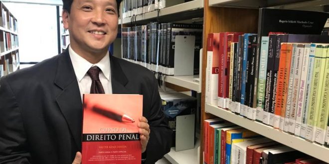 Valter Ishida posa para foto com um livro de direito penal em mãos