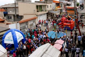 multidão reunida em meio a brinquedos e atividades em rua de carapicuíba