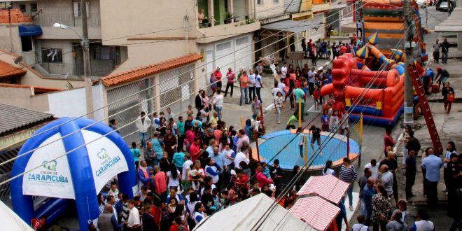 multidão reunida em meio a brinquedos e atividades em rua de carapicuíba