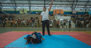 dois atletas no tatame enquanto um árbitro faz orientações