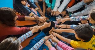 crianças sentadas em círculo com as pernas esticadas e roçando os pés