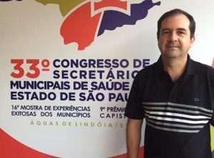 alexandre pierroni posa diante de banner com o logo do congresso