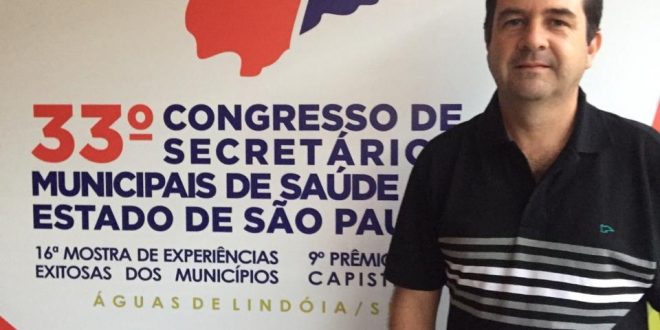 alexandre pierroni posa diante de banner com o logo do congresso