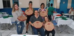 participantes do jantar posam com caixas de pizza em mãos