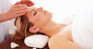 uma mulher deitada e de olhos fechados com um par de mãos sobre sua face realizando um procedimento reiki